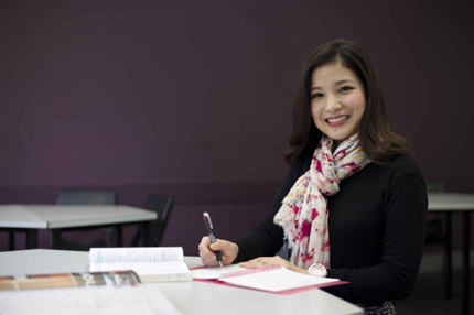 Student on campus smiling holding books