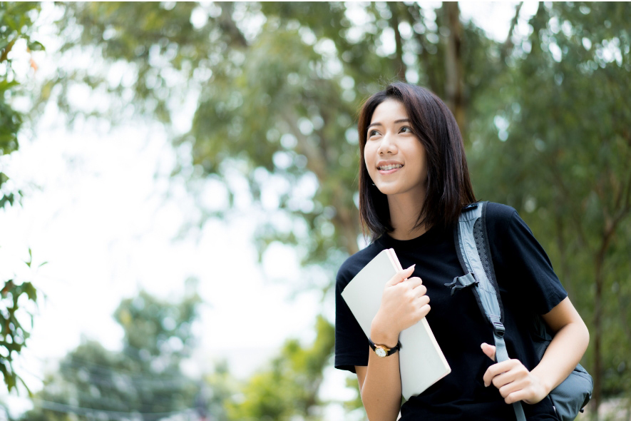 Student outside carrying books happy