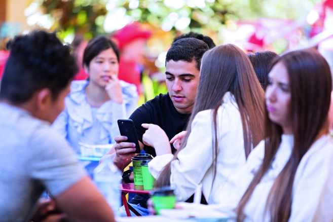 Students sitting on grass using phone