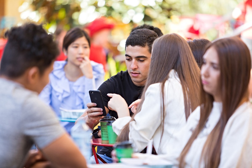 students using phone at cafe